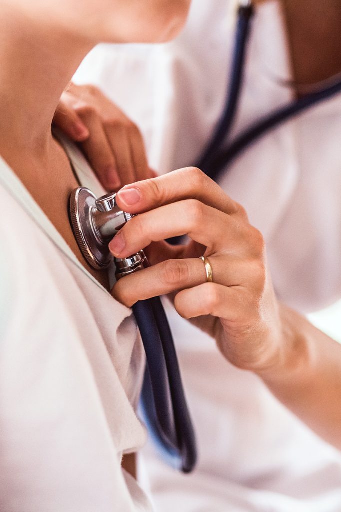 Stopwatch Urgent Care doctor checking patient with stethoscope